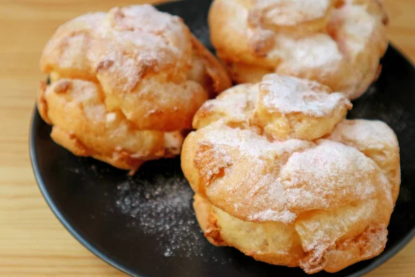 Closeup French Cream Puffs Black Plate Bestrooid Met Icing Sugar — Stockfoto