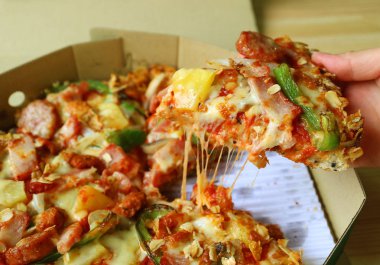 Kutudan bir dilim esnemiş peynirli pizza seçiyorum.
