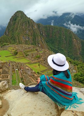 Uçurumda Dinlenen Kadın Machu Picchu Inca Harabelerine, Cusco 'ya, Urubamba' ya, Peru, Güney Amerika 'daki Arkeolojik siteye bakıyor.