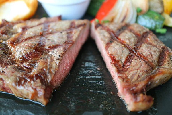Closeup texture of cut medium grilled ribeye steak served on hot stone plate