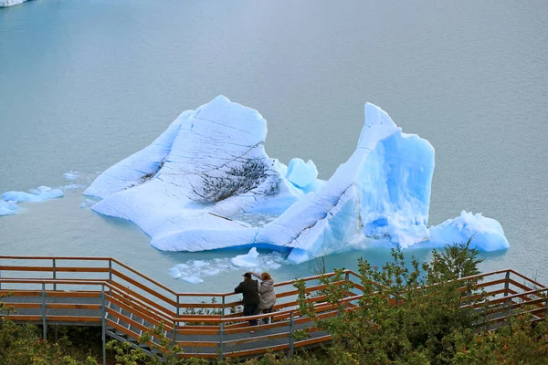位于阿根廷El Calafate的Los Glaciares国家公园Agentino湖上的巨大冰山前的观景台前的两名游客 — 图库照片