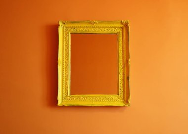 Sarı antika boş fotoğraf çerçevesi turuncu renkli duvarda izole edilmiş.
