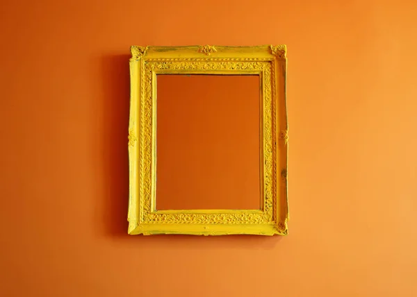 Yellow antique empty photo frame isolated on orange colored wall