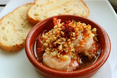 Lezzetli İspanyol stili sarımsaklı karides ya da arka planda dilimlenmiş ekmekli Gambas al Ajillo