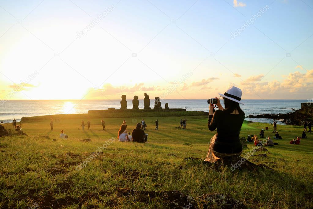 Female Tourist Taking Photos of the Famous Sunset Scene at Ahu Tahai, Archaeological site on Easter Island, Chile