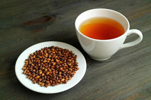 Japon Mugicha ya da Arpa Çayı Bir tabak kavrulmuş arpa ile ahşap masa