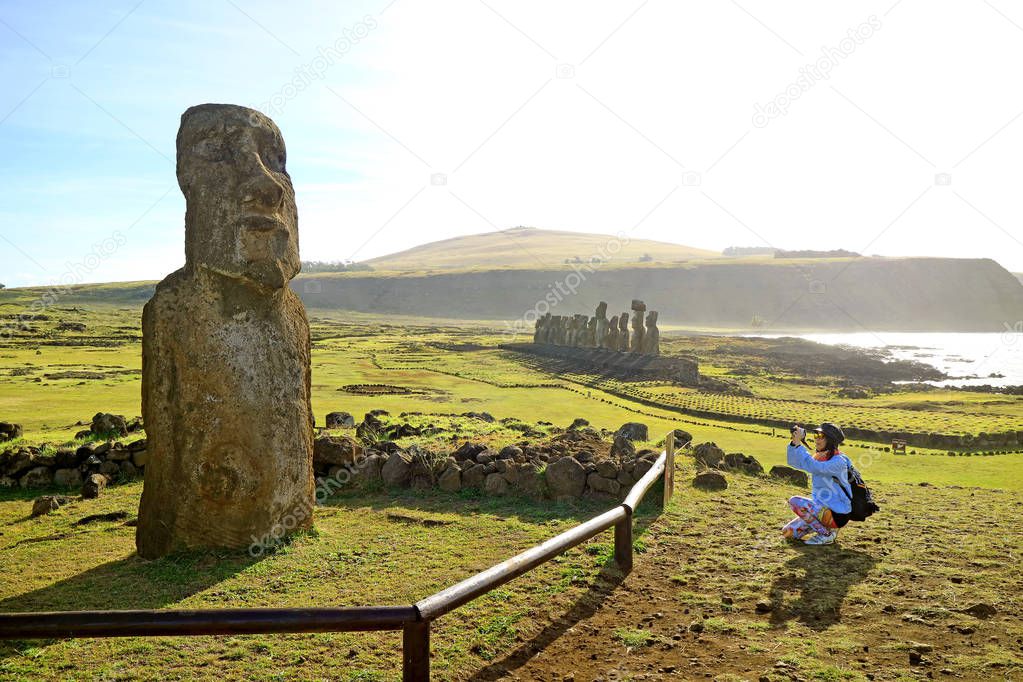 Female tourist taking photo of solitary Moai near the famous 15 Moais on the platform of Ahu Tongariki, Archaeological site on Easter Island, Chile