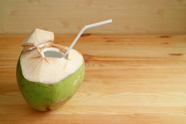 Açık kahverengi ahşap masada beyaz pipetli taze hindistan cevizi.