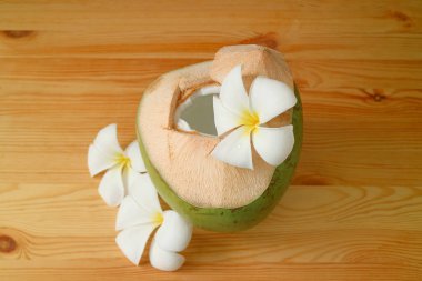 Lezzetli meyve suyu ve meyveli taze hindistan cevizi ahşap masada Plumeria çiçekleriyle servis edilir.
