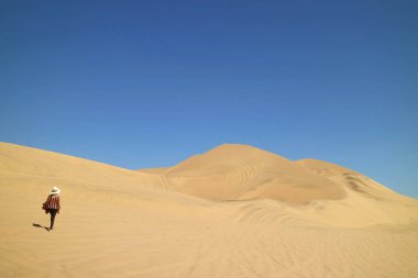 Güney Amerika 'nın Ica bölgesindeki Huacachina çölünün kumullarında yürüyen bir kadın.
