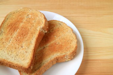 Tahta masada servis edilen iki parça kızarmış tam buğday dilimlenmiş ekmek.