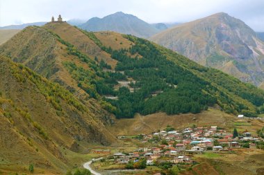 Village of Stepantsminda with the curvy road up to the famous Gergeti Trinity Church, Caucasus, Georgia clipart