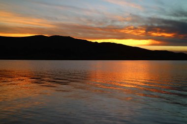 Puno, Peru, Güney Amerika 'daki Titicaca Gölü' ne yansıyan etkileyici Günbatımı Sonrası Parıltısı