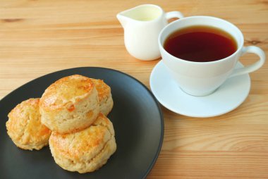 Bir tabak portakallı çörek ve ahşap masada bir fincan sıcak çay.
