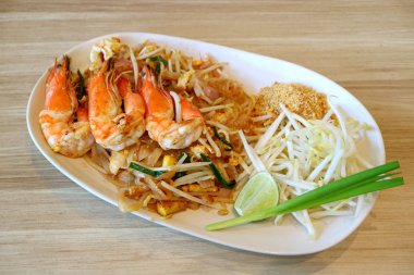 Pad Thai ya da Tayland usulü kızarmış erişte. Tahta Masada servis edilen nehir karidesleriyle tepelenmiş.