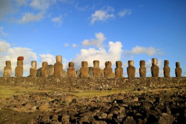 15 devasa Moai heykelinin arkasında fotoğraf çeken kadın turist Ahu Tongariki 'nin sabah güneşinde, Paskalya Adası, Şili