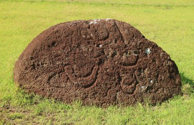 Terk Edilmiş Pukao ya da Moai Heykeli 'nin Topknot' u, Şili 'nin Paskalya Adası Arkeolojik Alanı Puna Pau Volkanı' ndaki Kızıl Scoria Taşı üzerinde Petroglyph ile birlikte.