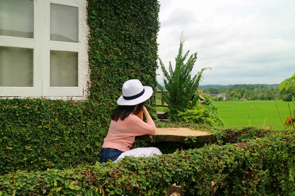 Kobieta Siedząca Tarasie Drzewa Pozostawia Pokryty Wiejski Dom Patrząc Pole — Zdjęcie stockowe