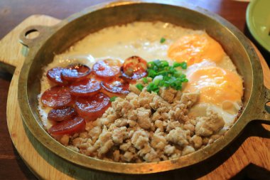 Kızarmış domuz eti, kızarmış yumurta ve tavada servis edilen dilimlenmiş Çin sosisi.