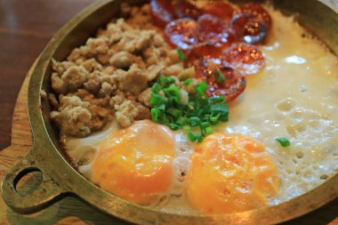 Arka planda kızarmış domuz eti ve dilimlenmiş Çin sosisiyle sahanda yumurta.