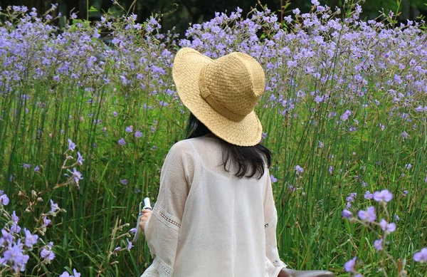 女人戴着草帽 骑着自行车 望着美丽的紫罗兰花田 — 图库照片