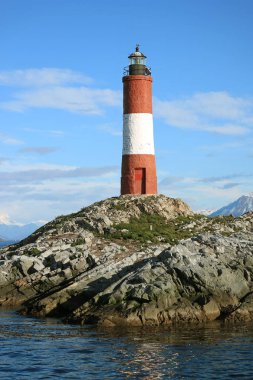 Kayalık adalardaki kırmızı ve beyaz çizgili Les Eclaireurs deniz fenerinin dikey görüntüsü, Beagle Channel, Ushuaia, Tierra del Fuego, Arjantin