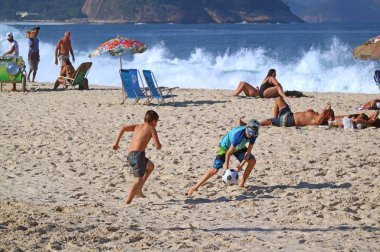 Birçok insan Rio de Janeiro, Brezilya 'daki Copacabana plajındaki faaliyetlerinden keyif alıyor.