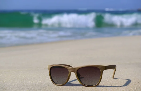 Zonnebril Het Strand Met Wazige Spetterende Golven Achtergrond — Stockfoto