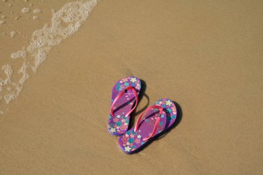 Bir çift canlı mor parmak arası terlik kumsalda dalgalı sandaletler, Copacabana plajı, Brezilya