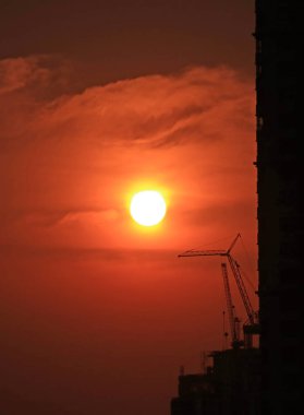 Bangkok, Tayland 'daki inşaat alanının siluetinin üzerinde koyu turuncu renkli gökyüzünde batan güzel güneş.