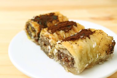 Üç parça lezzetli Baklava tatlısının ahşap masada servis edildiği bir yer.