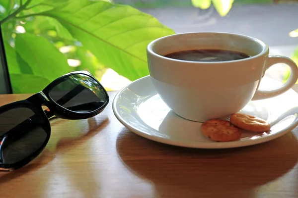 Cup Hot Coffee Black Sunglasses Wooden Table Window Blurred Green — 스톡 사진