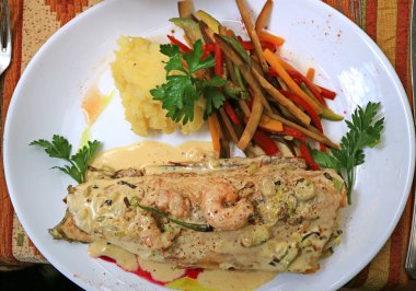 Beyaz tabakta kremalı karides soslu kavrulmuş alabalık manzarası.