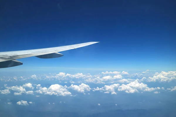 飛行中に飛行機の窓から見える飛行機の翼と鮮やかな青い空と純粋な白い雲の見事な景色 — ストック写真