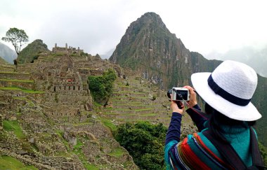 Machu Picchu 'daki İnka harabelerinin fotoğrafını çeken genç bir kadın.