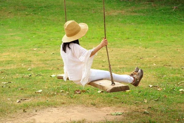 在公园里的木制秋千上休息的女人 — 图库照片