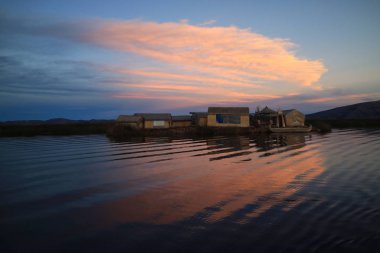 Sunset, Puno, Peru, Güney Amerika 'daki Titicaca Gölü' nde yüzen Uros Adaları 'nın çarpıcı görüntüsü