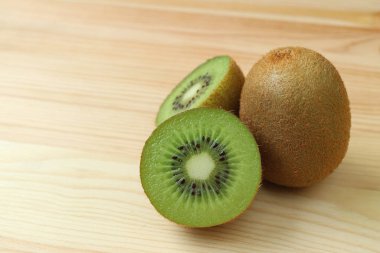 Taze olgun kivi meyvesinin kapalı kesitleri ve ahşap masada izole edilmiş meyveler.