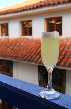 Bir bardak Peru Pisco Sour arka planda eski bina, eski şehir Cusco, Peru