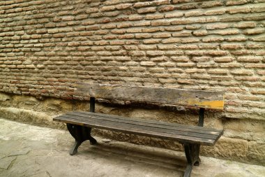 Eski tuğla duvarın önündeki boş ahşap bank