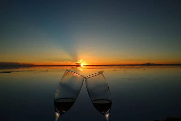 在日落时分 两只玻璃杯叮当作响 以庆祝南美洲玻利维亚Uyuni盐滩的镜像效应 — 图库照片
