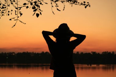 Karanlık çöktüğünde rıhtımda dinlenen bir kadının silueti.