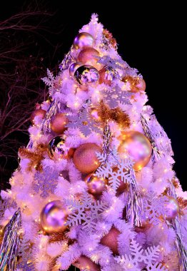Pembe renkli ışıklar parıltılı ve parlak süslemelerle dolu büyük Noel ağacı.