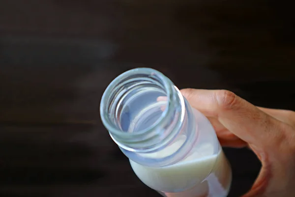 Tenuta Della Mano Dell Uomo Aperto Bottiglia Latte Sfondo Marrone — Foto Stock