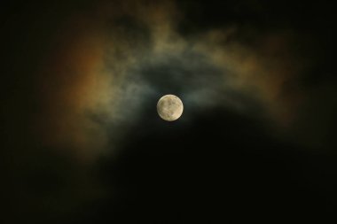 Dolunay karanlık gökyüzünde ay ışığı bulutlara yansıyor.