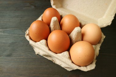Karton kutuda organik tavuk yumurtası. Koyu kahverengi ahşap masa üzerinde izole edilmiş.