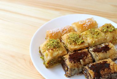 Beyaz tabak üzerinde birçok çeşit Baklava hamur işi, yazı ve tasarım için boş alanı olan ahşap masa üzerinde servis edilir.