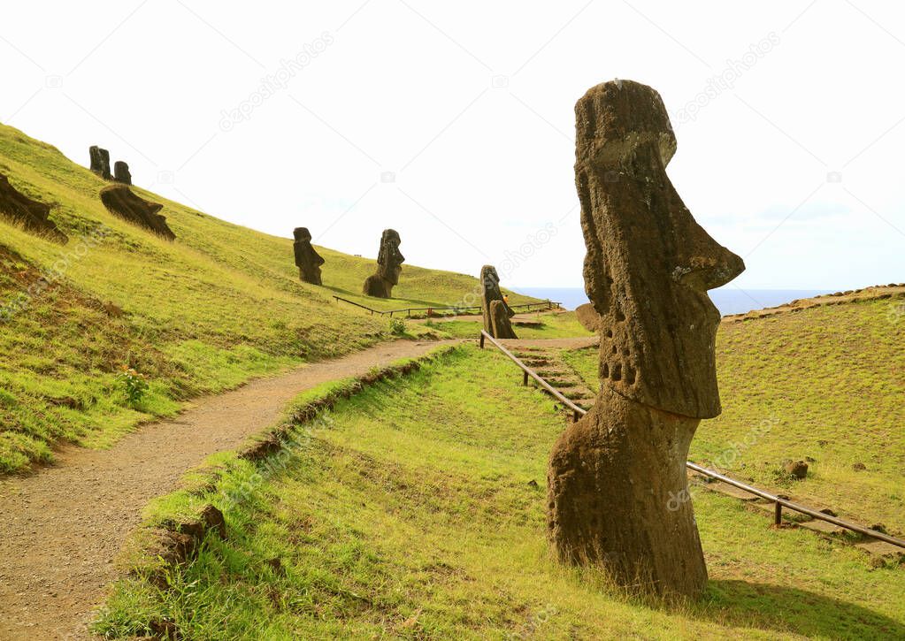 Sightseeing path among large group of abandoned giant Moai statues on the slope of Rano Raraku Volcano, Easter Island, Chile