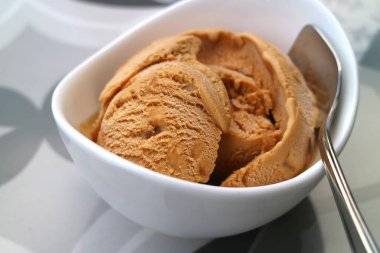 Yakın plan ev yapımı karamelli dondurma, beyaz kasede.