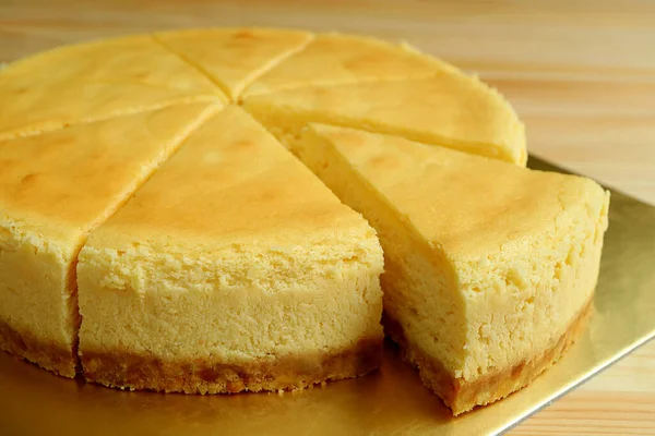 ケーキ全体からカットクリーミーな黄色のプレーン焼きチーズケーキのスライスを閉じます — ストック写真